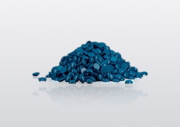 Custom blue hard wax beans in a loose pile on a white studio surface — an optional shade of the same bead