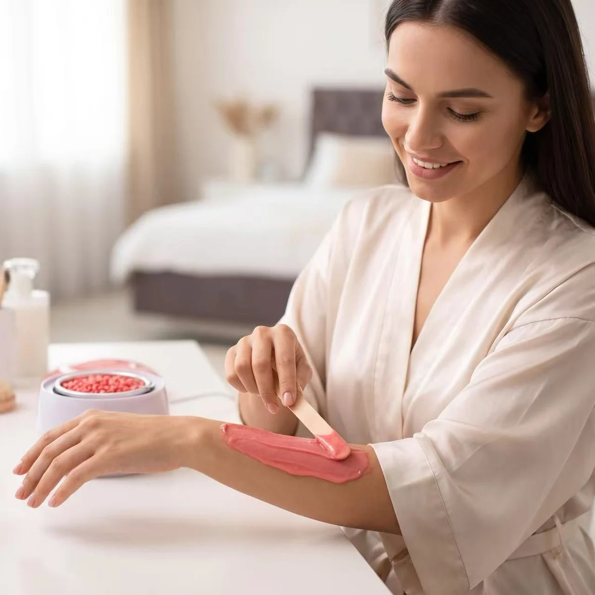 A thin layer of warm consumer-grade hard wax being applied to the forearm at home