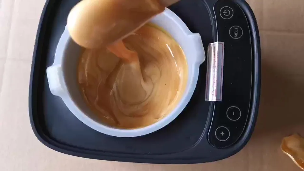 Golden A1 hard wax being stirred in a wax heater pot