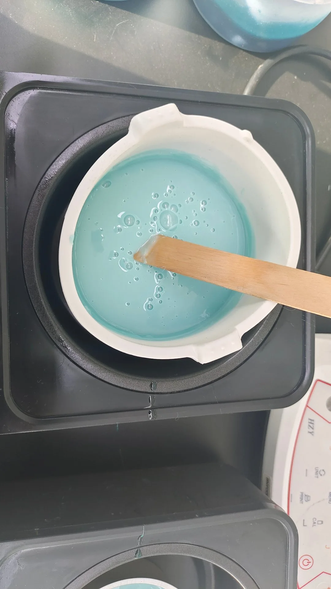 BeauTome lab - stirring melted teal hard wax in a test pot