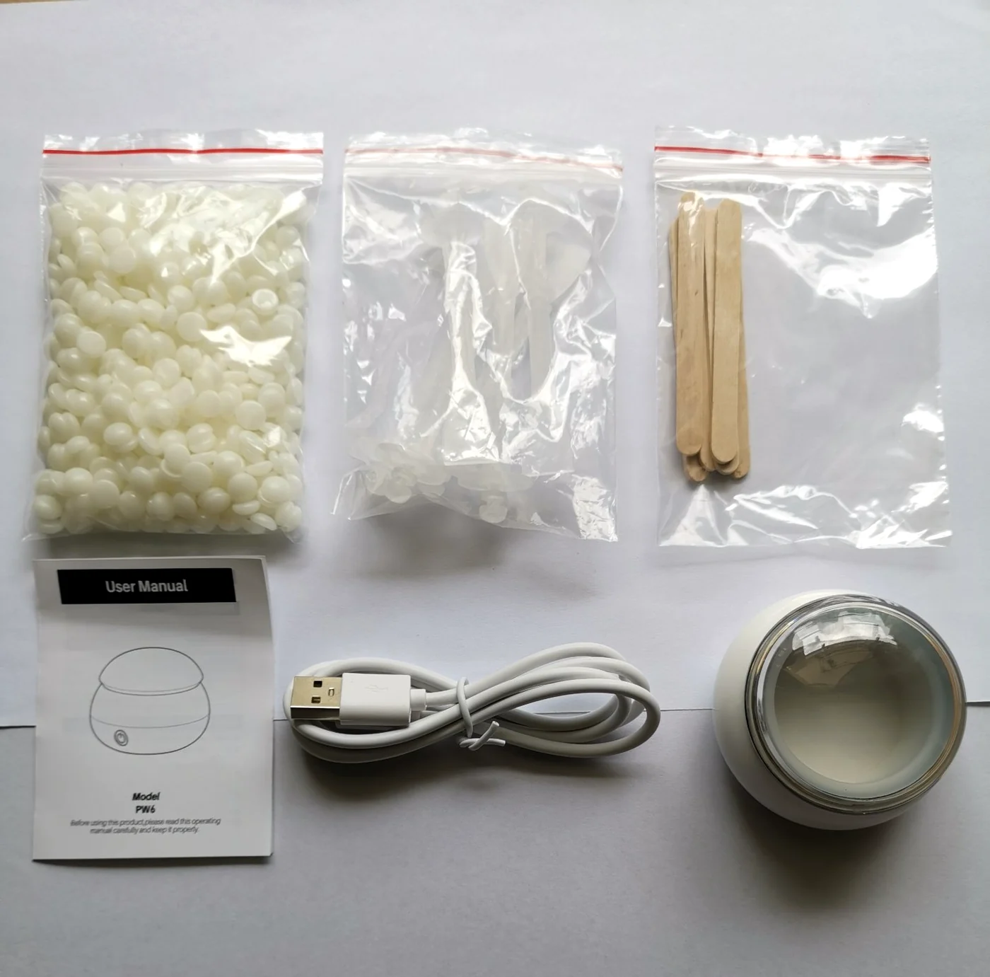 PW6 nose wax kit contents laid out: USB mini wax heater, Formula A1 hard wax 50 g bag, wooden wax applicator sticks, clear nose wax rods and USB cable