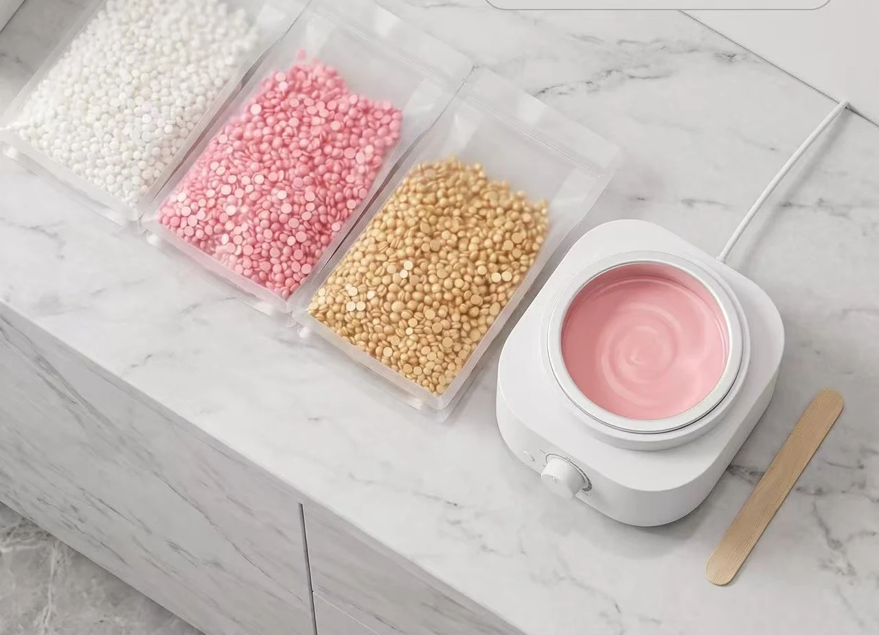 A1 rosin-free hard wax beads in white, pink and gold pouches beside a wax heater and spatula